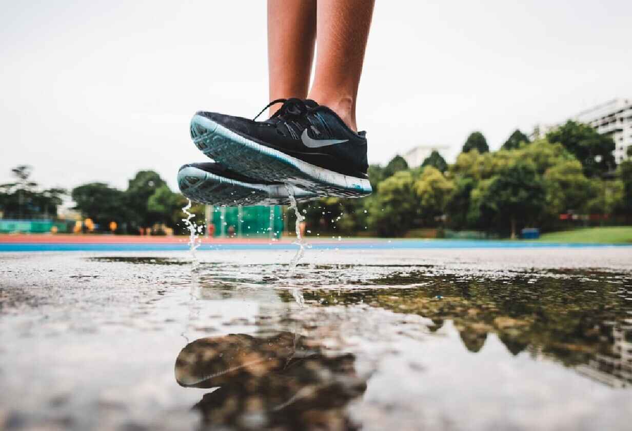 мъж с маратонки на Nike скача над локва