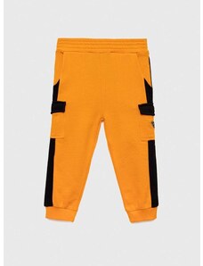 Детски памучен спортен панталон Guess в оранжево с десен