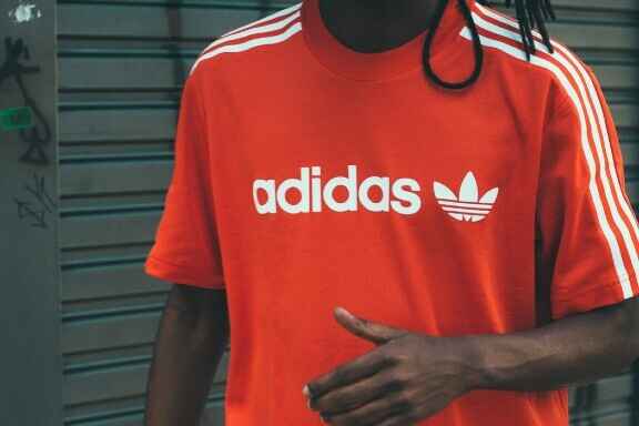 мъж с червена тениска с лого на adidas
