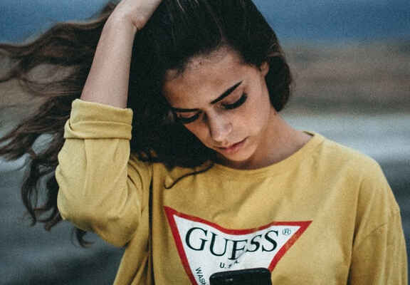 жена с тъмна коса и жълт суитшърт с лого на Guess
