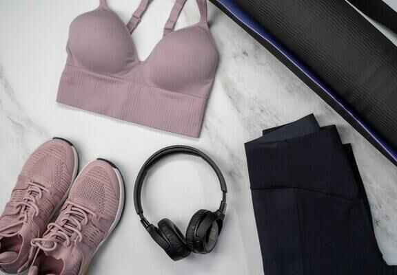 дамски розов спортен сутиен, розови маратонки, черни слушалки, черен клин
