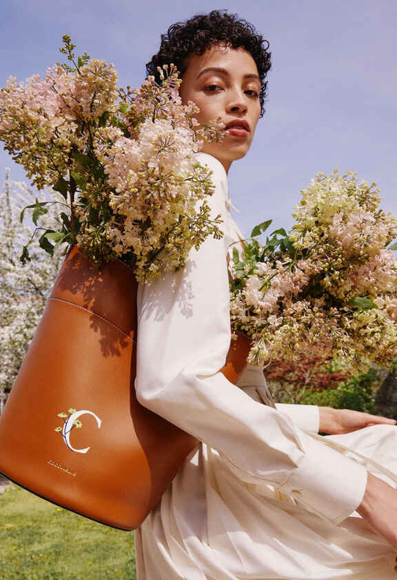 жена с бяла рокля и кафява чанта с цветя